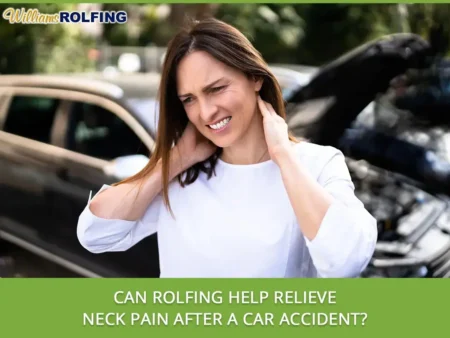 Woman in white shirt outdoors holding her neck with a pained expression near a car accident scene